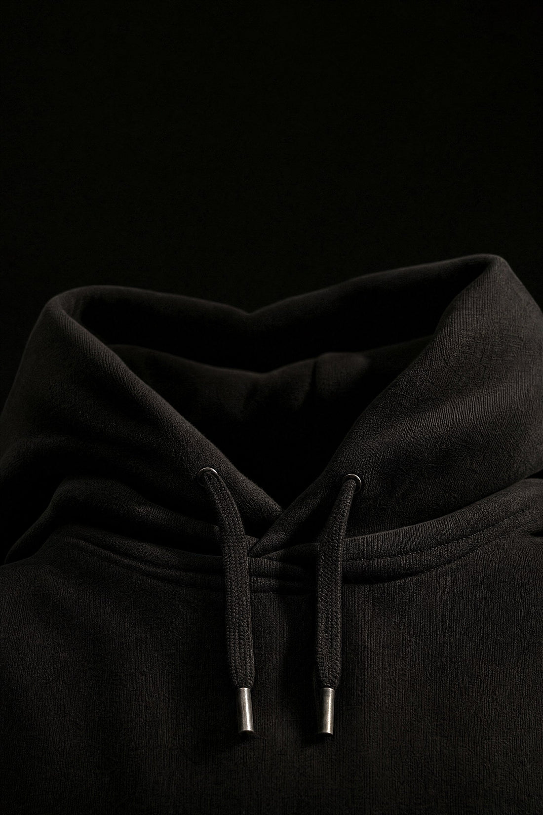 Close up of a black Odda hoodie showing the hood and drawcords