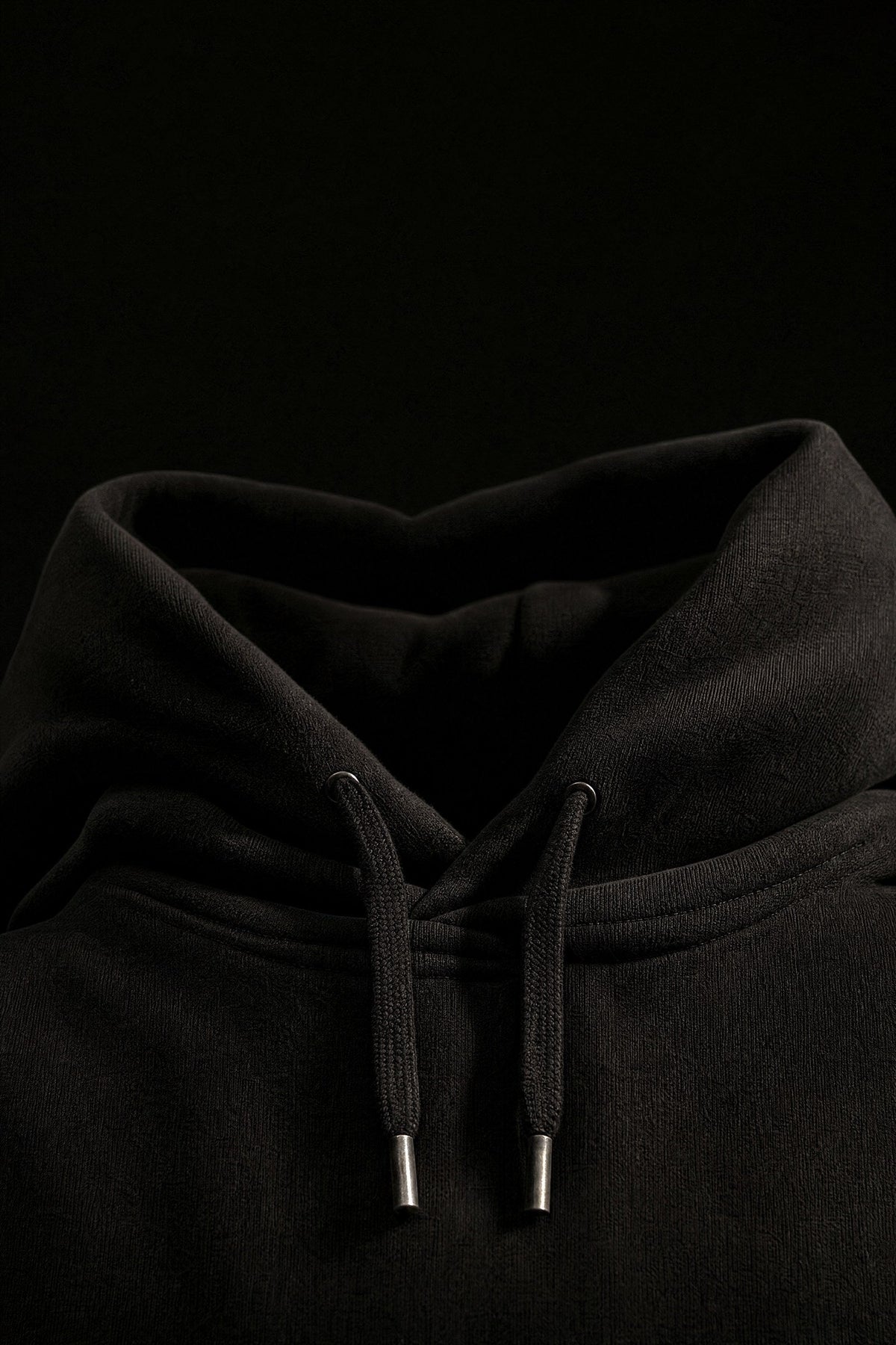 Close up of a black Odda hoodie showing the hood and drawcords