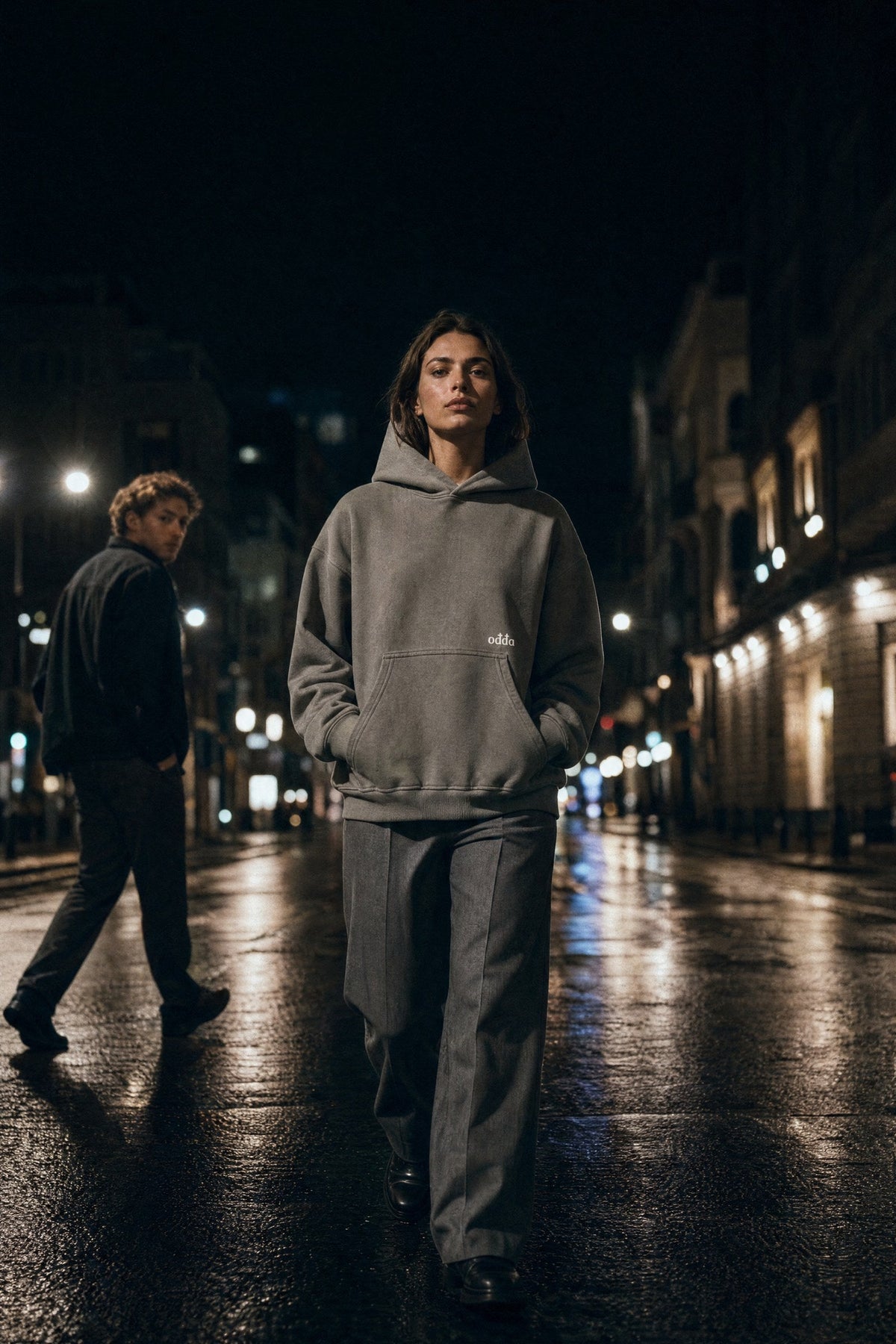 Woman in an oversized grey Odda hoodie on a street in the evening